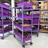 A purple MegaMaxx PRO 600mm x 400mm Bale Arm Crate Storage Trolley Shelving Unit with four tiers, equipped with castor wheels for mobility.